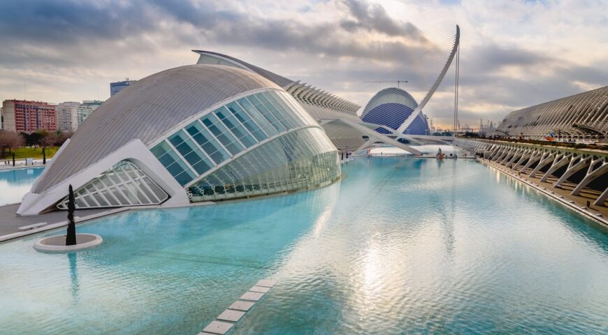 Panoramic cinema in the city of sciences of Valencia, Spain, visited by tourists next to the museum of sciences of the city in the background, at dawn with clouds and sun.