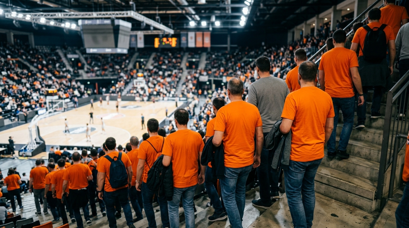 Aficionados con camisetas naranjas bajando por las escaleras de la grada de un pabellón de baloncesto.